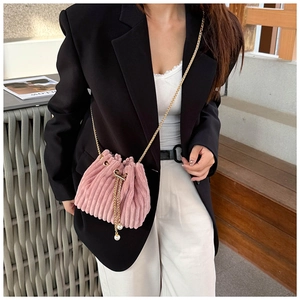 Detailed close-up of pink corduroy bucket bag with pearl drawstring and gold chain strap