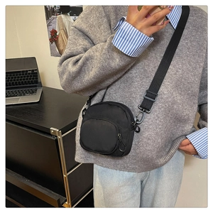 Close-up of lightweight black nylon crossbody bag featuring waterproof material and zippers