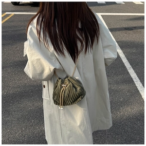 Detail of dark green corduroy bucket bag with gold chain and pearl drawstring accents