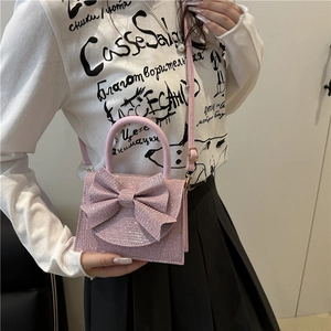 Elegant pink glitter crossbody bag with a large bow detail shown on a model