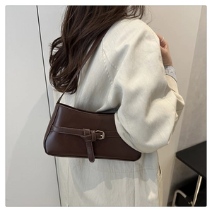 Dettaglio della borsa baguette marrone scuro con texture in pelle opaca e fibbia d'oro
