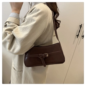 Dettaglio di una borsa a spalla marrone scuro vintage con fibbia e nodo decorativo
