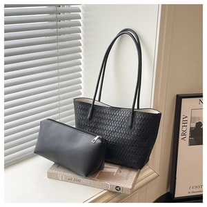 Detailed view of black woven tote bag and matching clutch set on a stylish windowsill