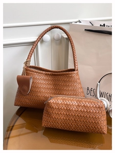 Détails du sac cabas tressé marron avec sa pochette assortie sur une table