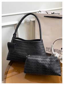 Détail d'un grand sac cabas noir tressé avec pochette zippée assortie sur une table