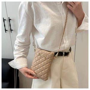Gros plan du sac bandoulière matelassé beige avec nœud doré et bandoulière en chaîne