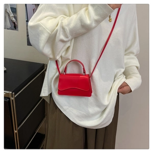 Chic red mini crossbody bag styled with a white sweater and brown long skirt