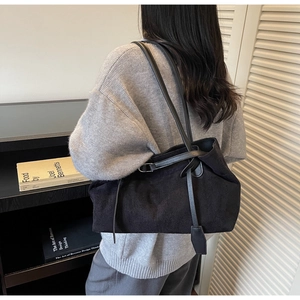 Chic black matte suede tote bag with long straps worn on shoulder by model in cozy interior