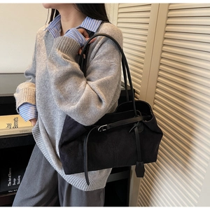 Close-up of black frosted suede tote bag with silver buckle detail on a model's shoulder