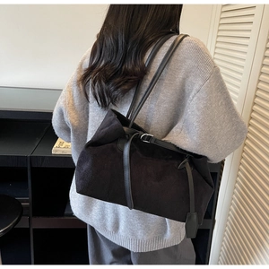 Detail of minimalist black matte tote bag with slim leather straps and silver buckle