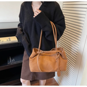 Detail of vintage brown suede tote bag featuring adjustable buckles and leather straps