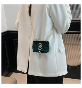 Détail d'un sac bandoulière en velours vert foncé avec motif matelassé et chaîne