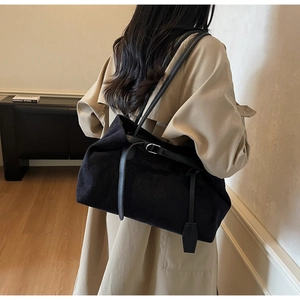Macro detail of black suede tote bag with slim shoulder straps and stylish metal buckle