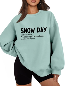 Detail of mint green oversized sweatshirt with snow day slogan and plush cotton texture
