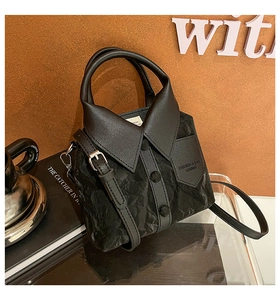 Close-up of black shirt-shaped bucket bag featuring unique pleated PU leather and button detail