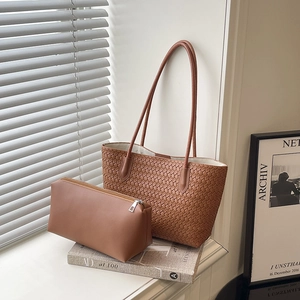 Brown woven tote bag with matching inner pouch on a white windowsill in soft lighting