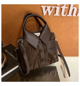 Close-up of dark brown leather handbag with creative shirt collar design and buttons