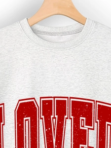 Close-up of ribbed crewneck and red LOVED letter print on grey heather sweatshirt