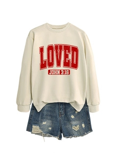 Close-up of crewneck sweatshirt with LOVED print and distressed denim shorts