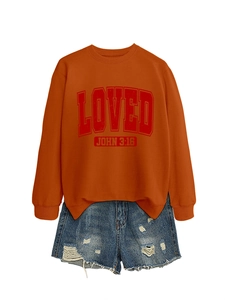 Close-up of bright orange crewneck sweatshirt with Loved print and distressed denim shorts