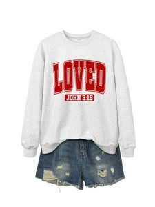 Flat lay of a white crewneck sweatshirt with red LOVED print and distressed denim shorts