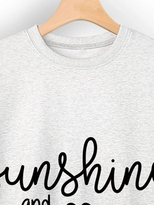 Close-up of ribbed crewneck and sunshine print on light grey knit sweatshirt fabric