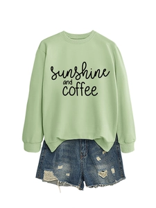 Detail of sunshine and coffee slogan on light green crewneck sweatshirt with denim shorts