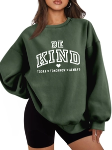 Gros plan détaillé du sweat-shirt vert foncé avec lettrage Be Kind et texture du tissu