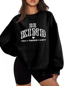 Gros plan du texte BE KIND imprimé sur un sweat-shirt noir à col rond et bords-côtes