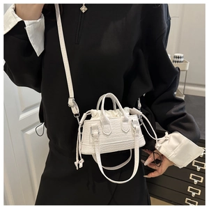 Detail of white mini bucket bag with crocodile texture and adjustable shoulder strap