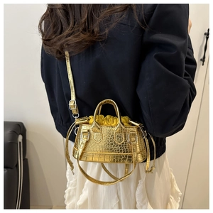 Golden crocodile embossed bucket bag with drawstring liner shown as a crossbody wear