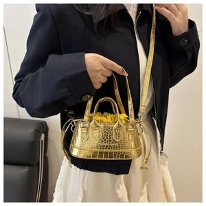 Detail of gold mini bucket bag with crocodile pattern and yellow drawstring closure