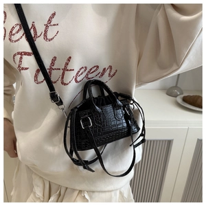 Detailed close-up of a black croc-effect mini bag with drawstring and shoulder strap