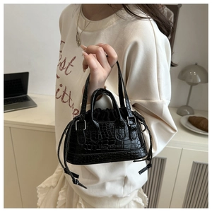 Détail du mini sac à main noir avec texture crocodile et boucle de cordon argentée