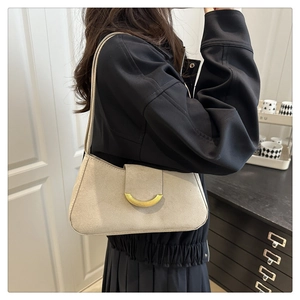 Detail view of smooth grey suede texture and gold crescent metal buckle on the bag