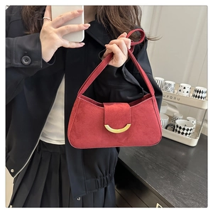 Detail of red suede shoulder bag featuring a striking gold crescent moon metal buckle