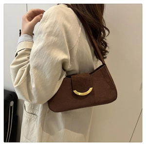 Close-up of deep brown suede shoulder bag featuring a half-moon golden metal buckle detail