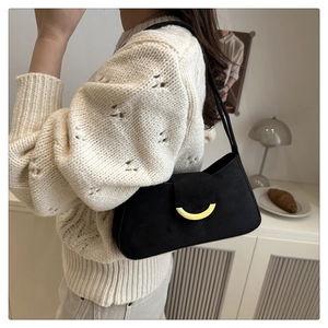 Detail of a minimalist black suede shoulder bag with a stylish gold magnetic buckle