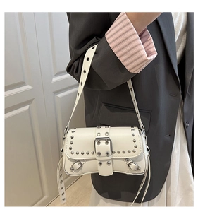 Detail of white studded underarm bag with silver rivets and eyelet shoulder strap