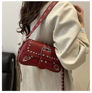Detail of dark red punk style shoulder bag with silver studs and metal grommets on strap