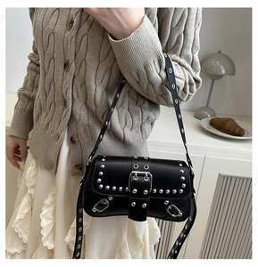 Detail of a black leather punk shoulder bag with silver studs and eyelet straps