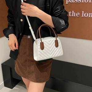 White quilted crossbody bag with brown handles and V-shaped stitching for elegant daily wear