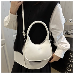 Detail of white half-moon crossbody bag featuring gold-stamped lettering and smooth texture