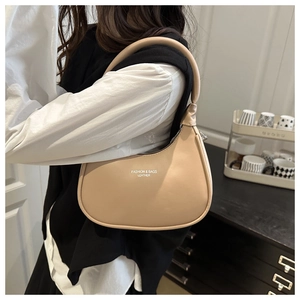 Detail of beige leather crescent shoulder bag with FASHION & BAGS branding and soft texture