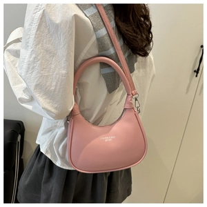 Pink crescent shoulder bag shown from back view on model with stripe vest
