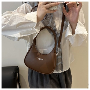 Mirror selfie showing brown leather crescent handbag with a detachable shoulder strap