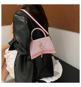 Dettaglio della borsa a tracolla rosa glitterata con logo SS dorato e base curva su modella