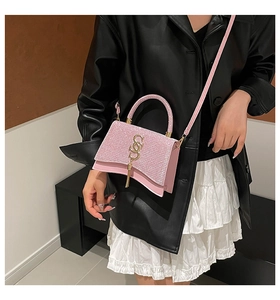 Borsa a tracolla rosa con paillettes, logo dorato e nappa indossata da una modella