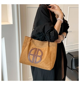 Detalle del gran logo circular en el bolso tote de ante marrón con correas finas