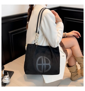 Large black faux suede tote bag with golden chain strap and circular AB logo detail